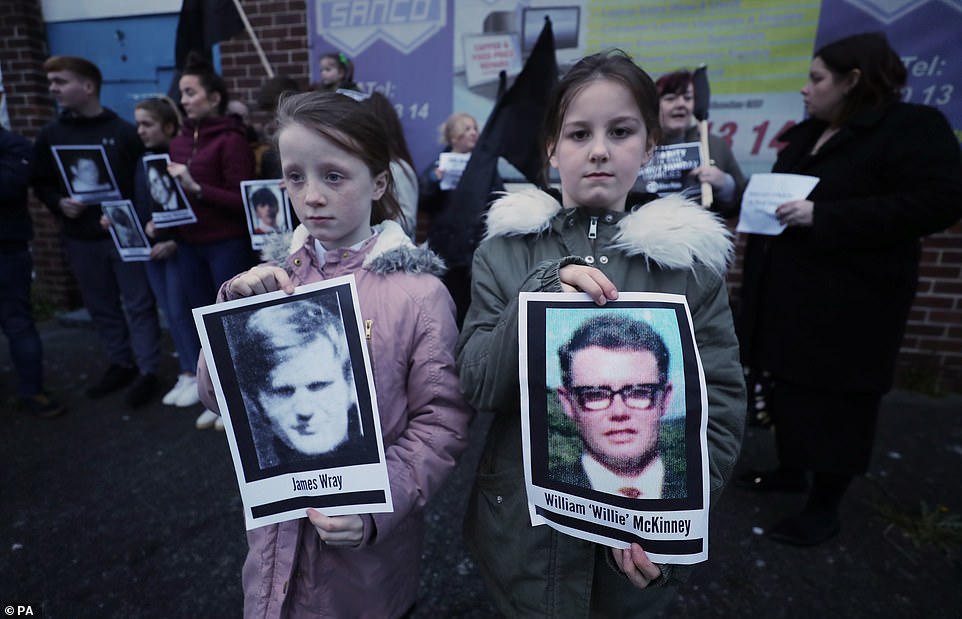 Two children hold pictures of Bloody Sunday victims James Wray and William McKinney during a vigil in West Belfast Northern Ireland