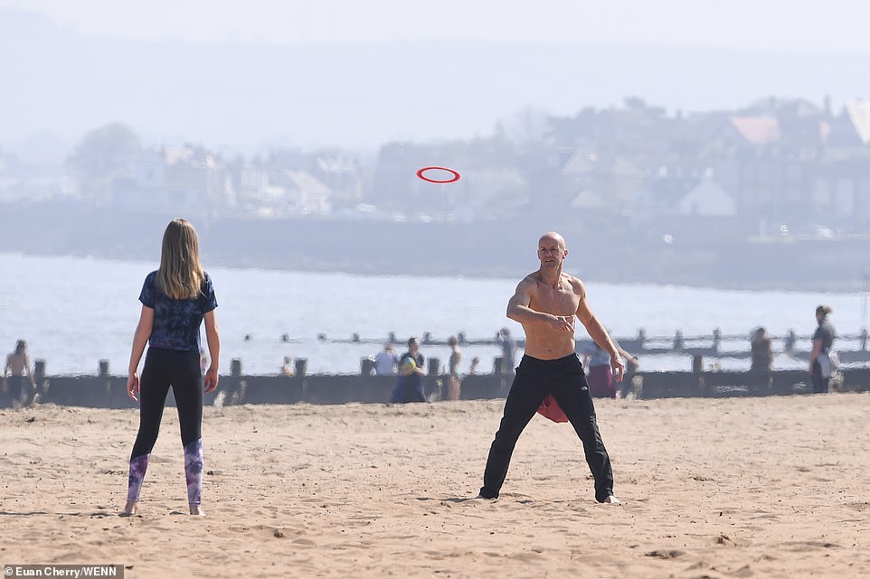 A father and daughter throw a frisbee at Portobello beach in Edinburgh